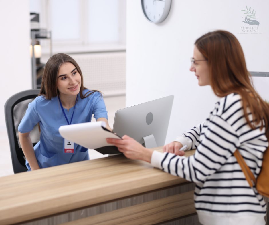 A Sandy Hill Wellness team member handing a patient a receipt at the front desk